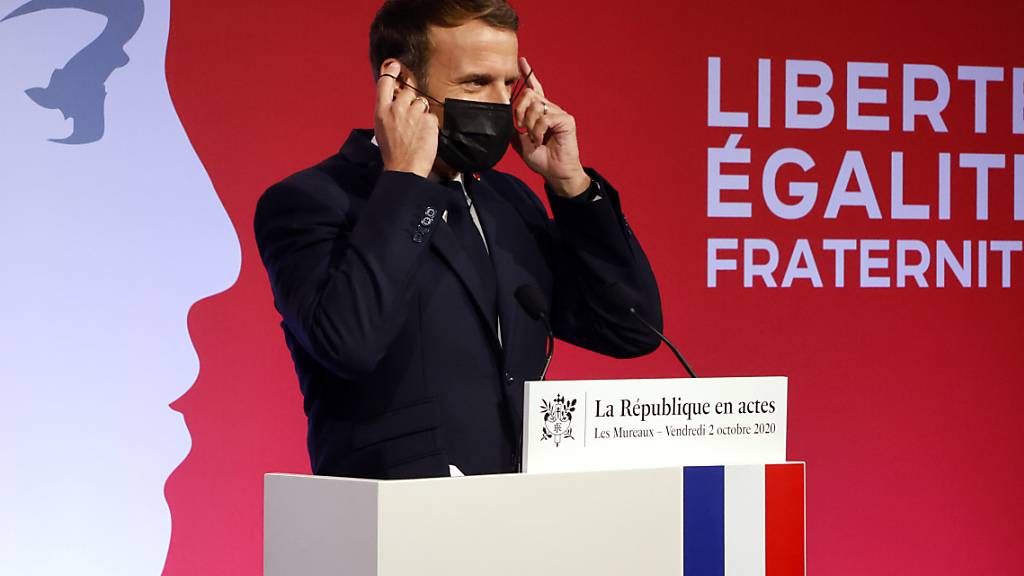 Emmanuel Macron, Präsident von Frankreich, zieht seine Maske an, nachdem er in Les Mureaux eine Rede gehalten hat. Frankreich will nach den islamistischen Terroranschlägen mit vielen Toten in den vergangenen Jahren verstärkt gegen Radikalisierung vorgehen. Foto: Ludovic Marin/POOL AFP/dpa