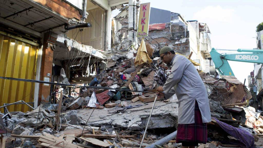 Ein Mann begutachtet die Schäden nach Überschwemmungen. Foto: Firdia Lisnawati/AP/dpa