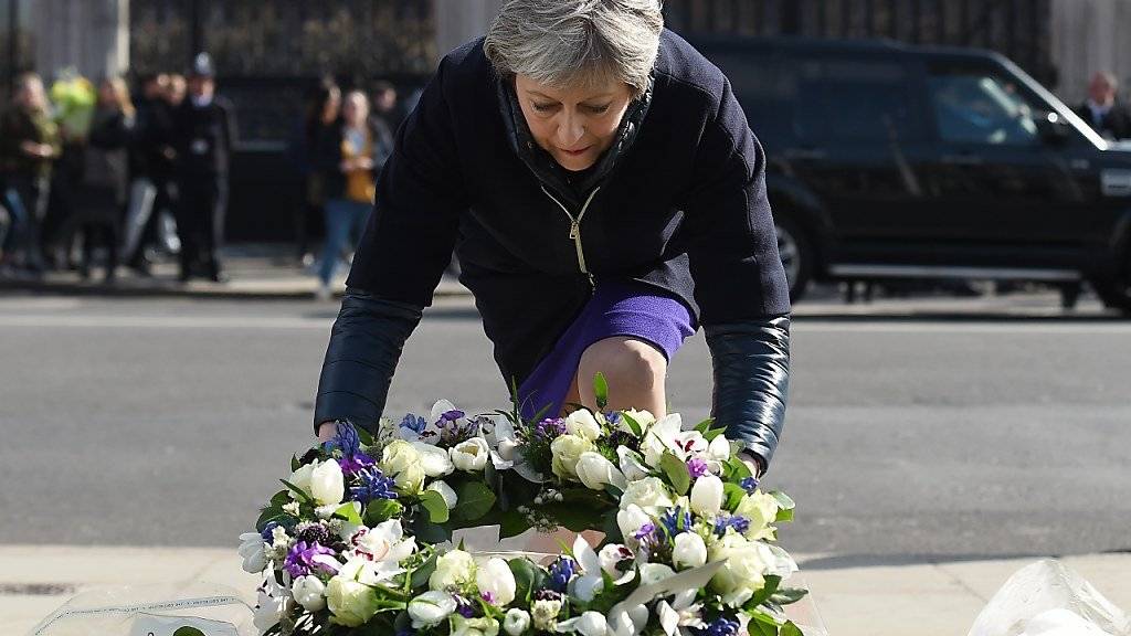 Im Gedenken an die Opfer des Terroranschlags in London vor einem Jahr legt die britische Premierministerin Theresa May vor dem Parlamentsgebäude Blumen nieder.