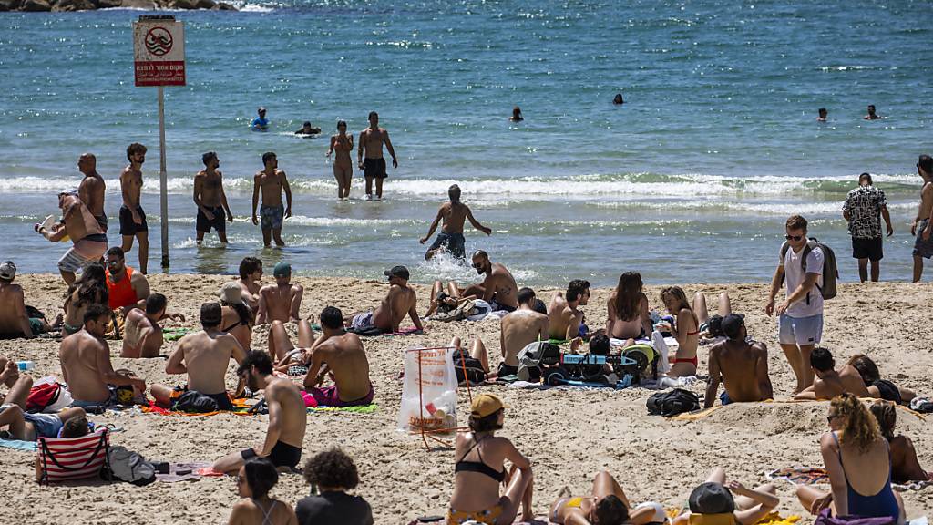 Menschen verbringen den Tag in der Sonne am Strand in Tel Aviv. Durch die fortgeschrittene Impfkampagne in Israel werden die Corona-Maßnahmen immer weiter aufgehoben. Foto: Ilia Yefimovich/dpa