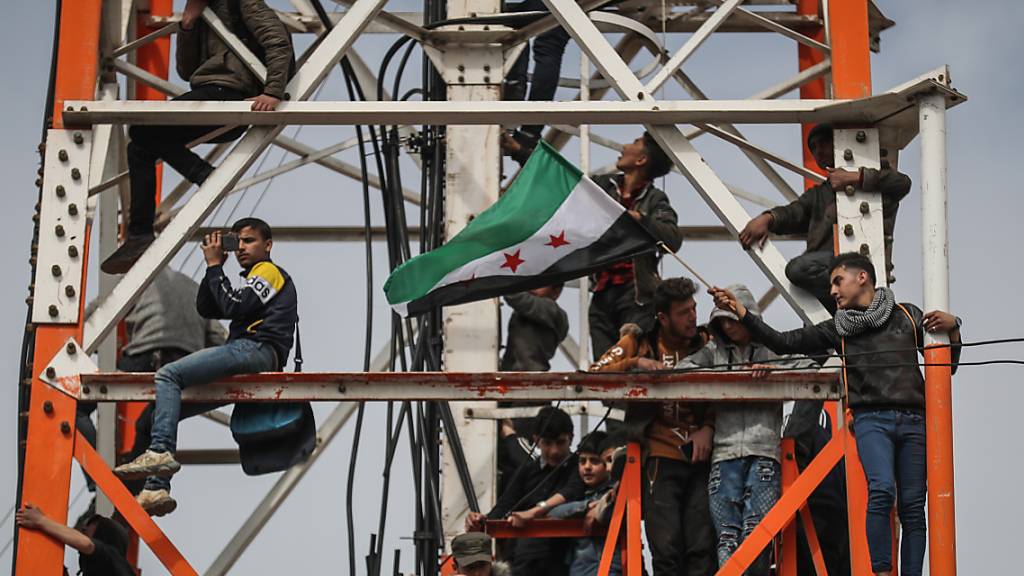 Ein Mann schwenkt in Idlib eine Fahne der syrischen Opposition während einer Massendemonstration zum zehnten Jahrestag des Beginns des syrischen Bürgerkriegs. Foto: Anas Alkharboutli/dpa