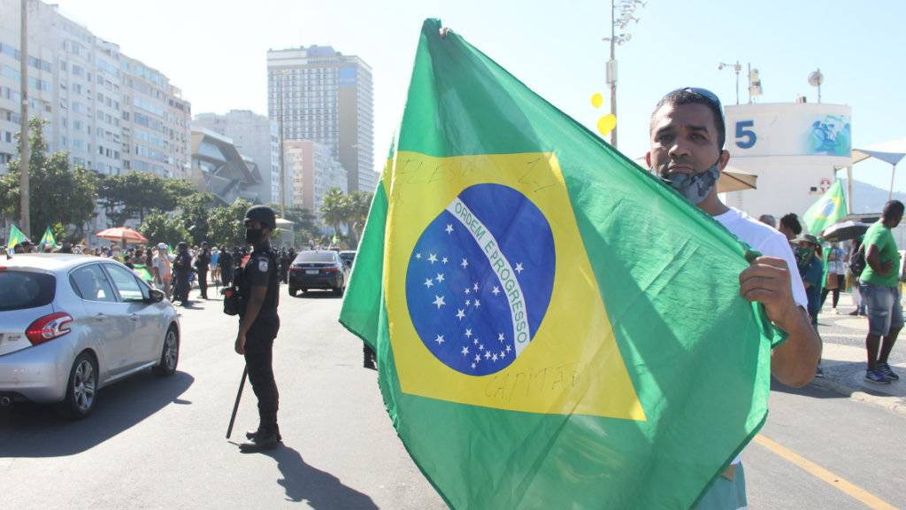 Ein Unterstützer des brasilianischen Präsidenten Bolsonaro hält bei einem Protest an der Copacabana eine brasilianische Fahne hoch. Foto: Fausto Maia/TheNEWS2 via ZUMA Wire/dpa