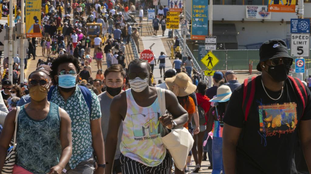 ARCHIV - Menschen drängen sich am Santa Monica Pier. In den USA nimmt die Zahl der an einem Tag erfassten Corona-Neuinfektionen wieder zu. Foto: Damian Dovarganes/AP/dpa