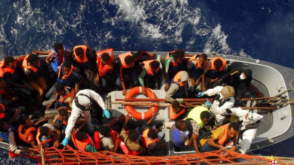 Von der italienischen Marine gerettete Flüchtlinge werden auf ein grössere Schiff gebracht. (Archiv)