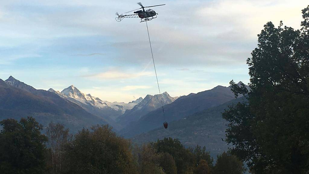 Ein Löschhelikopter holt im Umland von Savièse VS Wasser, um einen Waldbrand in der Nähe zu bekämpfen.