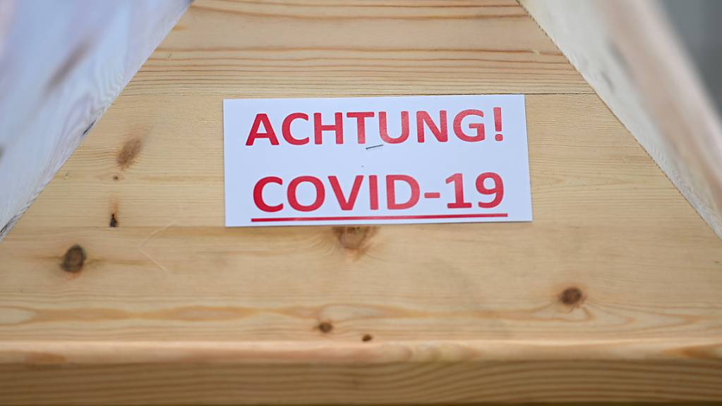 ARCHIV - Ein Sarg mit der Aufschrift «Achtung! Covid-19» steht in einem Raum im Krematorium, bevor der Sarg eingeäschert wird. Foto: Felix Kästle/dpa