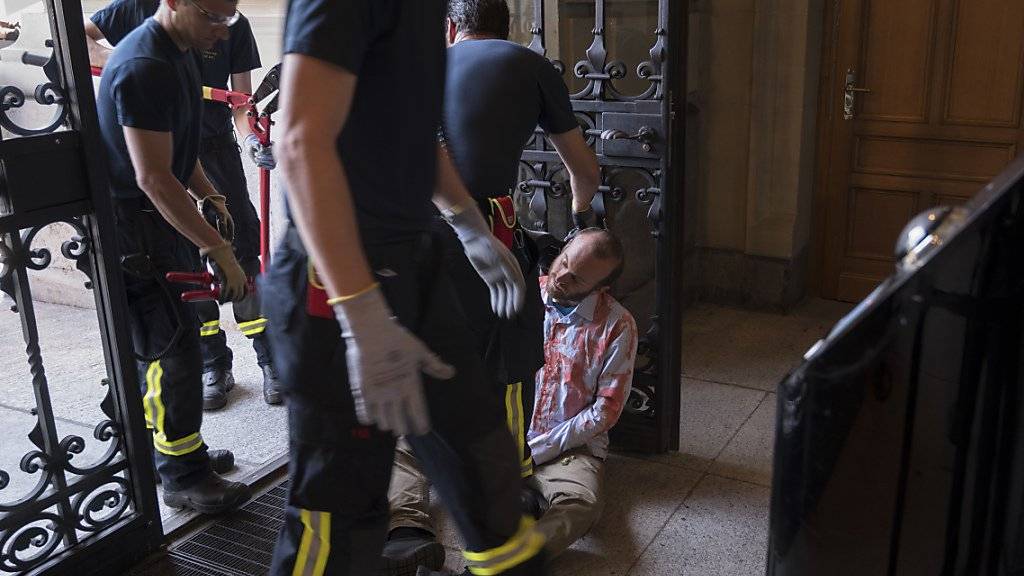 Ein Klimaaktivist von Extinction Rebellion wird von Feuerwehrleuten der Berufsfeuerwehr Bern befreit, nachdem er sich ans Eingangstor des Parlamentsgebäudes gekettet hatte.