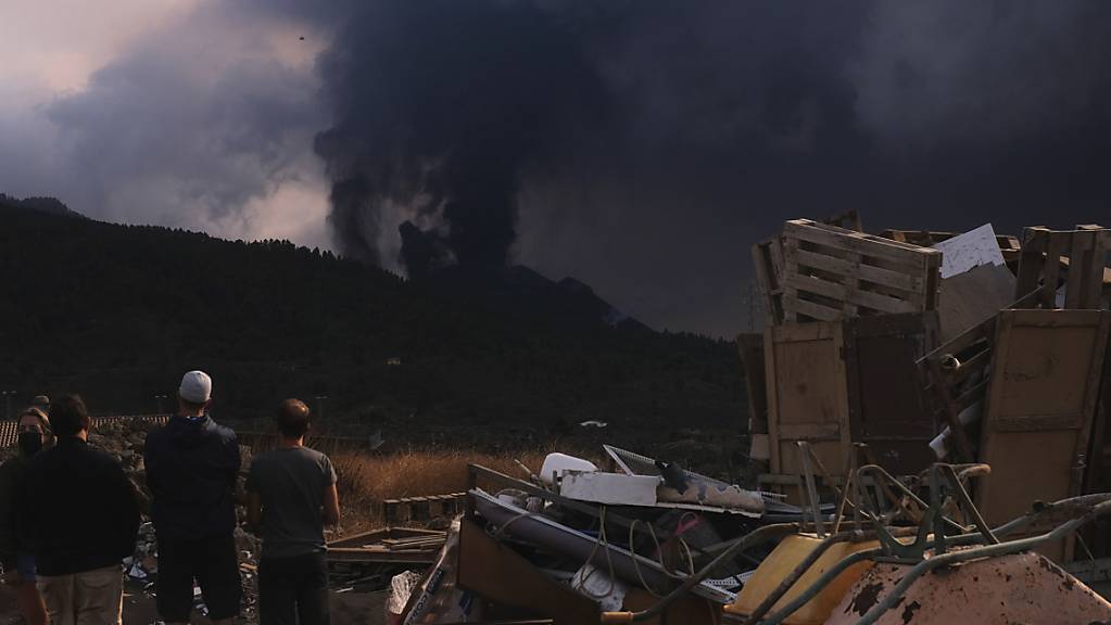 Menschen blicken von El Paso auf einen ausbrechenden Vulkan. Auf der Kanareninsel La Palma ist der Vulkanausbruch auch am Sonntag mit unverminderter Heftigkeit weitergegangen. Seit dem 19. September spuckt der Feuerberg in der Cumbre Vieja im Süden der Insel große Mengen Lava, Rauch und Asche aus. Foto: Daniel Roca/AP/dpa