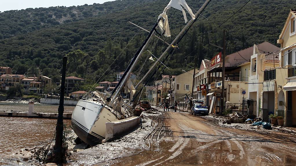 Eine Segelyacht liegt nach einem Sturm neben einer Straße an Land. Der Wirbelsturm «Ianos» und ein weiteres Sturmtief über der Nordägäis haben in weiten Teilen Griechenlands schwere Schäden verursacht. Foto: Nikiforos Stamenis/AP/dpa
