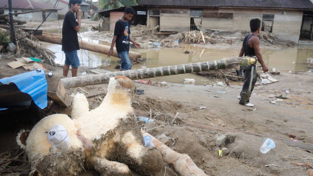 dpatopbilder - Menschen gehen durch ein von einer Sturzflut betroffenen Dorf in Nordsumatra. Foto: Binsar Bakkara/AP/dpa