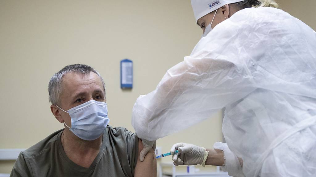 Eine medizinische Mitarbeiterin verabreicht einem Mann den Corona-Impfstoff Sputnik V. Foto: Pavel Golovkin/AP/dpa