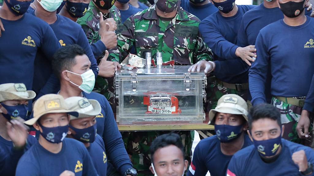 dpatopbilder - Personal der indonesischen Marine steht neben der Box mit dem Flugdatenschreiber des Sriwijaya Air Fluges SJ-182. Taucher haben nach tagelanger Suche auf dem Meeresgrund vor der Insel Java einen der Flugschreiber der verunglückten indonesischen Passagiermaschine geborgen. Foto: Dita Alangkara/AP/dpa