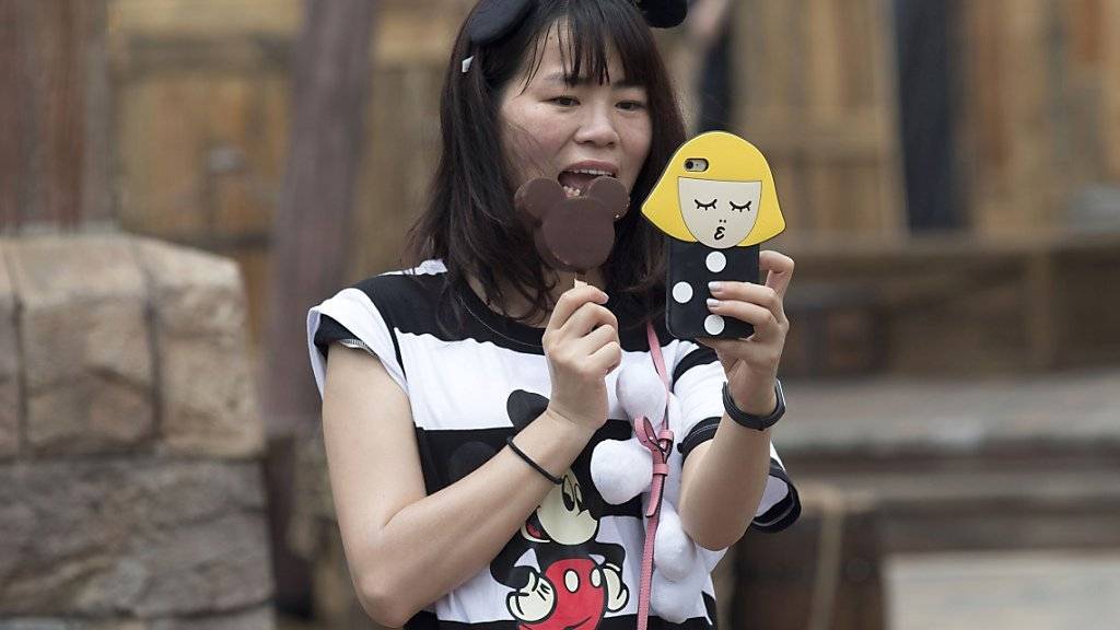 Eine Besucherin des ersten Disney-Parks in China posiert für ein Selfie.