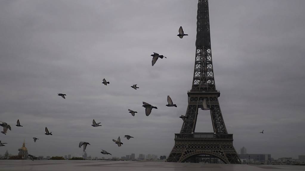 ARCHIV - Tauben fliegen am Eiffelturm vorbei. Wegen der Covid-19-Pandemie ist die Wiedereröffnung des Eiffelturms vorerst abgesagt worden. Foto: Thibault Camus/AP/dpa