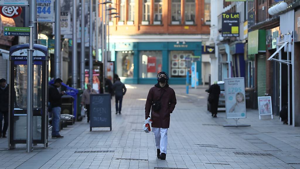 Ein Mann geht in einer Straße an geschlossenen Geschäften vorbei. Nordirland befindet sich in einem sechswöchigen Lockdown aufgrund der Corona-Pandemie. Foto: Brian Lawless/PA Wire/dpa