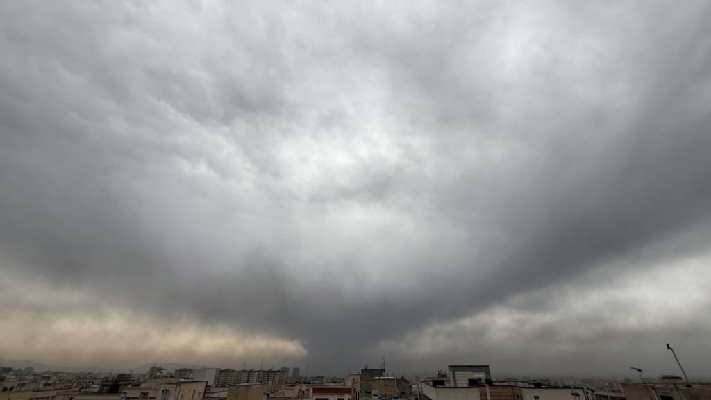 dpatopbilder - Rauchschwaden eines amerikanisch-israelischen Angriffs auf eine Ölanlage am späten Samstag sind am bewölkten Himmel zu sehen. Foto: Vahid Salemi/AP/dpa