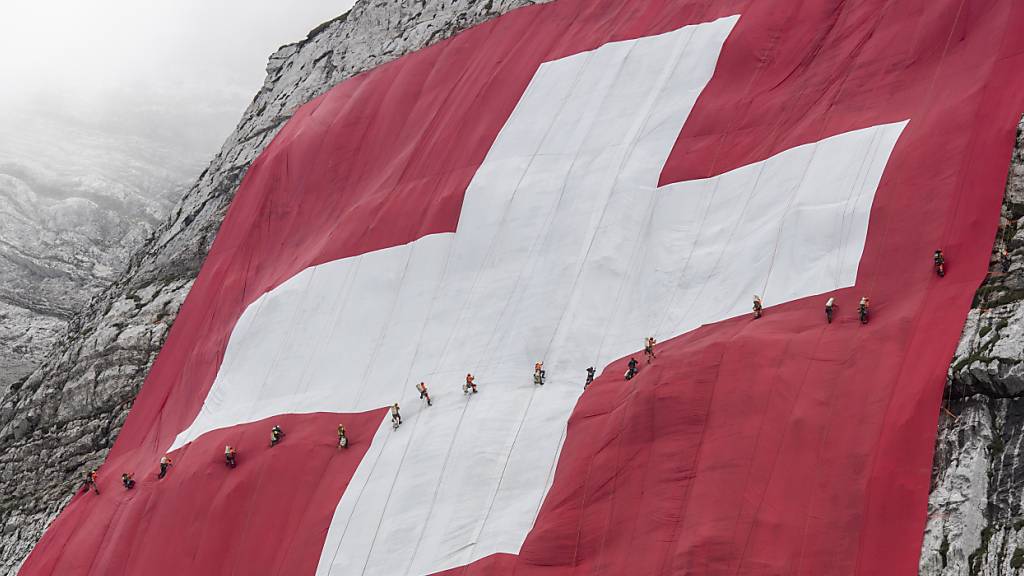 Arbeiter bewegten sich am 1. August 2019 auf der ausgerollten 6400 Quadratmetern grossen Schweizerfahne am Säntis. (Archivbild)