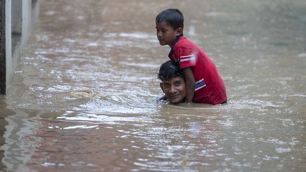 Ein Mann trägt seinen jüngeren Bruder durch eine überschwemmte Strasse in der nepalesischen Hauptstadt Kathmandu. (Archivbild)