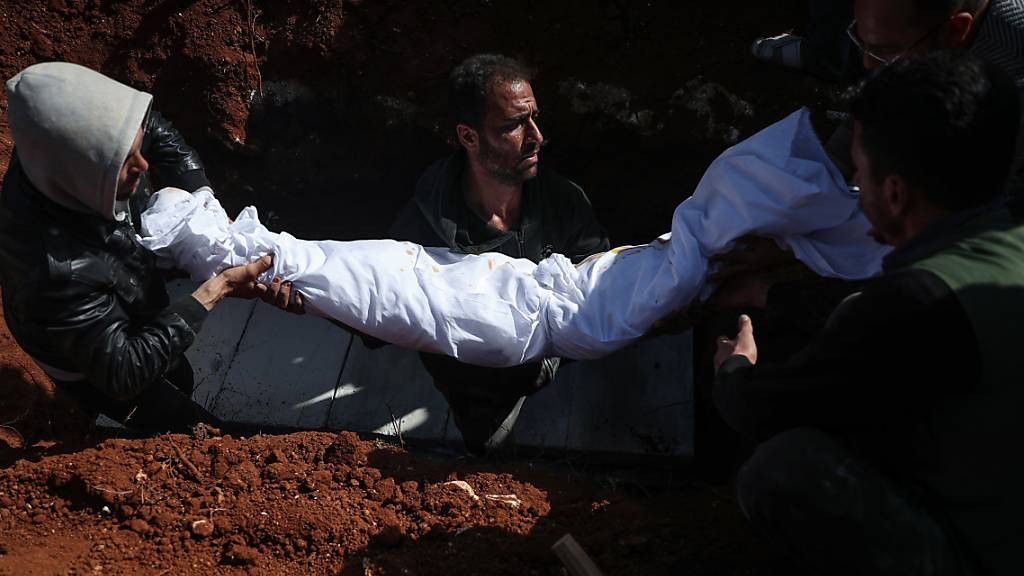 Syrische Männer tragen während einer Beerdigung auf einem Friedhof den Leichnam einer Person, die bei einem Raketenangriff auf ein Krankenhaus getötet wurden. In Syrien sind bei einem Angriff von Regierungstruppen auf ein Krankenhaus nach Angaben von Menschenrechtlern mindestens fünf Menschen getötet worden.