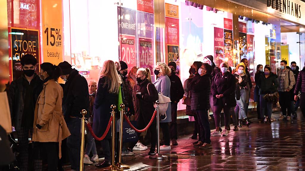 Menschen stehen am letzten Samstag vor Weihnachten auf der Oxford Street in London vor einem Geschäft Schlange. Foto: Stefan Rousseau/PA Wire/dpa