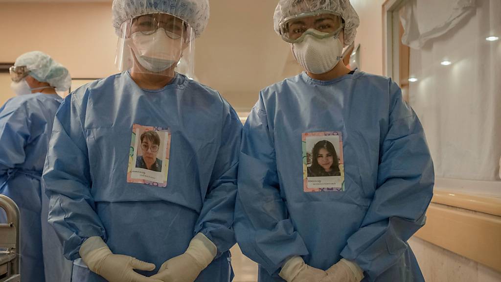 Dr. Lilian Revelez (l) und Maria Fernanda Negrete (r) stehen in Schutzkleidungen mit ihren Porträts vor der Intensivstation für Covid-19-Patienten in der Fachklinik für Lungen- und Atemwegserkrankungen INER. Foto: Jacky Muniello/dpa