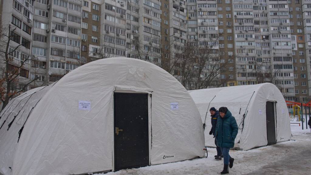 Anwohner gehen an einem der Zelte in Kiew vorbei, die der Katastrophenschutz nach den russischen Luftangriffen auf den ukrainischen Energiesektor aufgestellt hat. Foto: Efrem Lukatsky/AP/dpa/Archivbild