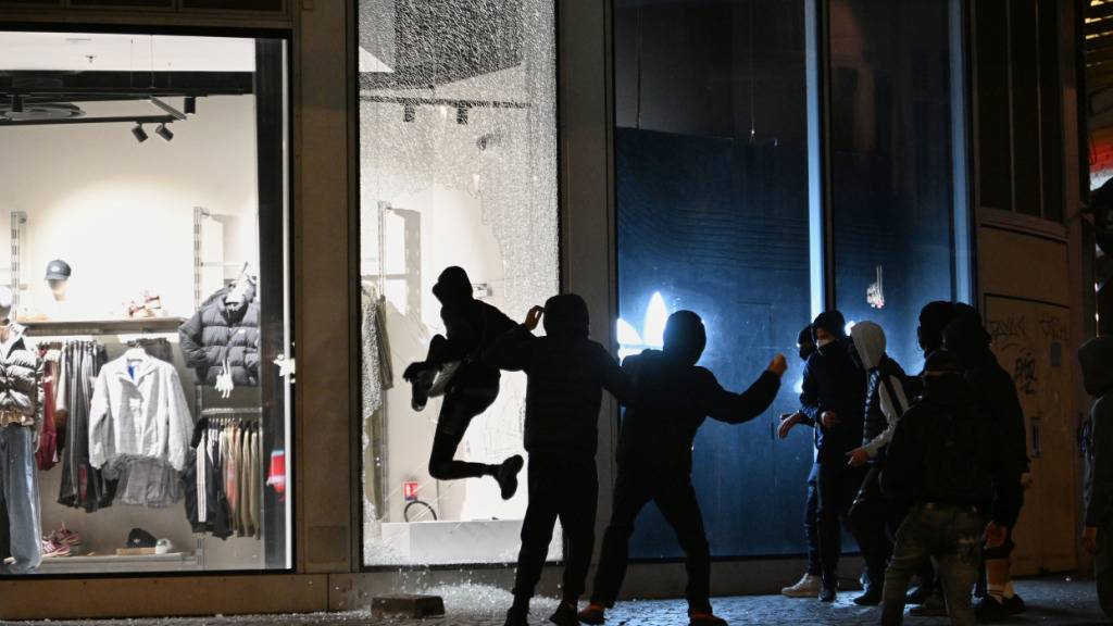 dpatopbilder - Jugendliche zerschlagen bei Zusammenstößen zwischen Demonstranten und der Polizei in Paris eine Schaufensterscheibe. Foto: Emma Da Silva/AP/dpa