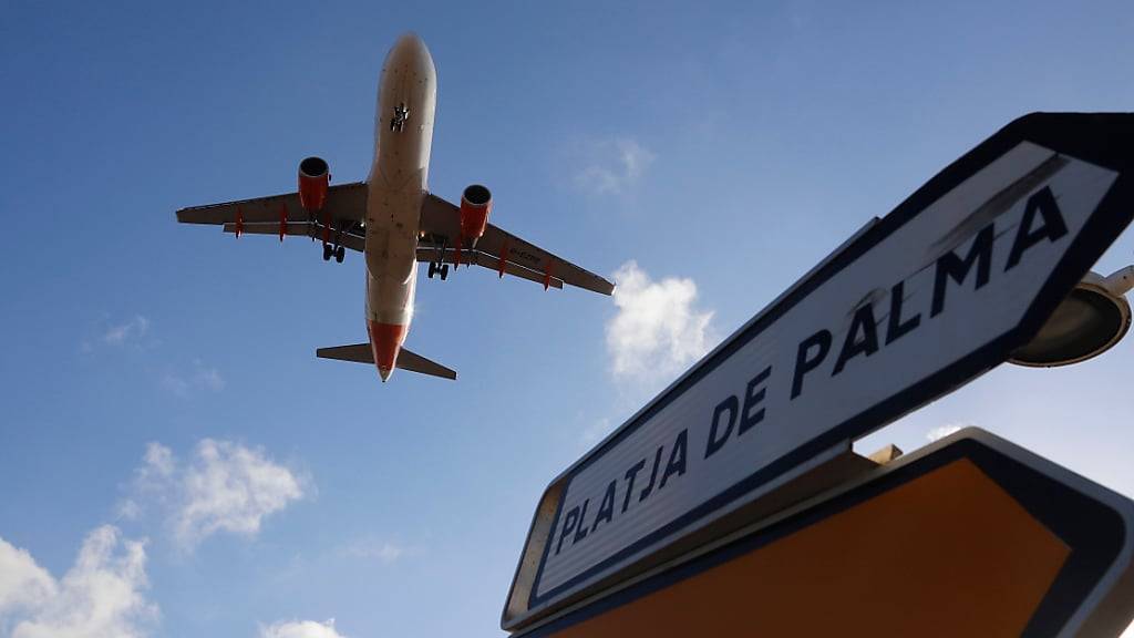 ARCHIV - Ein Flugzeug überfliegt bei der Landung auf Mallorca ein Schild, das die Richtung nach Playa de Palma anzeigt. Auf Mallorca ist erneut ein Türsteher einer Diskothek wegen eines tätlichen Angriffs festgenommen worden. Der circa 40 Jahre alte Mann soll einen deutschen Urlauber attackiert haben. Foto: Clara Margais/dpa