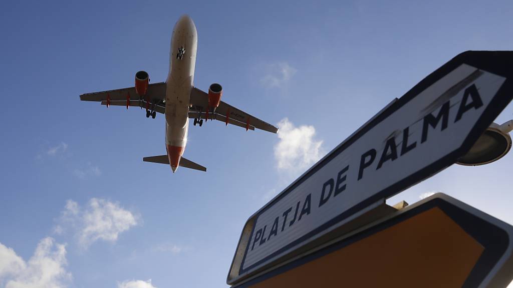ARCHIV - Ein Flugzeug überfliegt bei der Landung auf Mallorca ein Schild, das die Richtung nach Playa de Palma anzeigt. Auf Mallorca ist erneut ein Türsteher einer Diskothek wegen eines tätlichen Angriffs festgenommen worden. Der circa 40 Jahre alte Mann soll einen deutschen Urlauber attackiert haben. Foto: Clara Margais/dpa