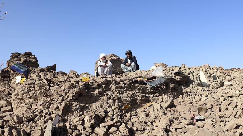 Afghanische Männer sitzen auf den Trümmern ihrer zerstörten Häuser nach einem Erdbeben in der Provinz Herat. Foto: Omid Haqjoo/AP/dpa