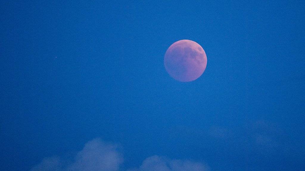 Der in rotem Licht erscheinende Mond von Luzern aus gesehen.